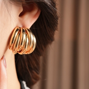 Close-up of elegant gold layered hoop earrings on a model with warm vintage aesthetic