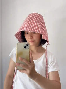 Macro shot of red gingham sun hat featuring wide brim and adjustable chin straps