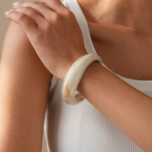 Detailed view of thick cream acrylic cuff bracelet with marble texture on model wrist