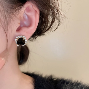 Gros plan d'élégantes boucles d'oreilles rondes en pierre noire avec halo de cristaux