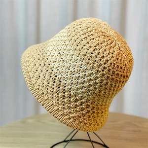 Detail view of beige woven straw bucket hat on a display stand with a soft background