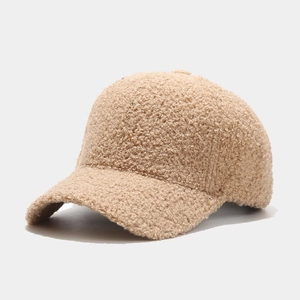 Close-up of curly lamb wool texture and warm fabric detail on beige baseball cap