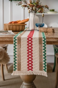 Close-up detail of Bohemian style woven table runner with tassels on a wooden surface