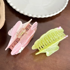 Pink marble and green clear acetate hair claws displayed on a decorative plate