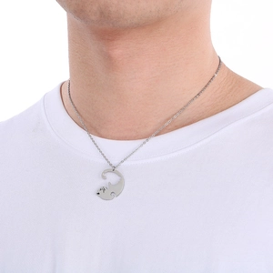 Gros plan détaillé d'un collier pendentif chat argenté porté par un homme en blanc