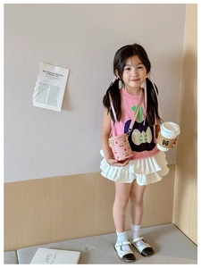 Pink cherry print bucket bag shown on a young girl in a warm indoor setting