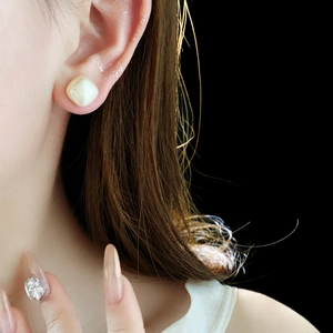 Detailed close-up of 14K gold plated square pearl stud earring on model with black background