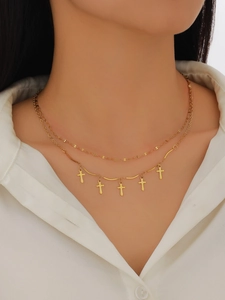 Close-up of double-layer gold necklace with five small cross pendants on model