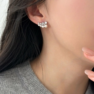 Close-up of curved silver stud earrings with gradient pearls and sparkling rhinestones