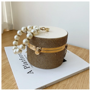 Detail of champagne gold rhinestone evening bag with elegant pearl ring handle