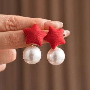 Close-up of handmade red fabric star earrings with elegant white pearl drop detail