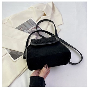 Detail showing plush black crossbody bag with faux fur trim and sleek shoulder strap
