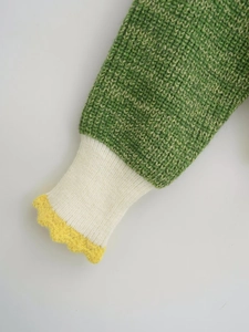 Macro shot of knit sweater cuff with grass green, cream white, and yellow wavy lace