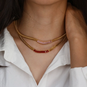 Détail de colliers chaîne cubaine dorée avec zircons rectangulaires roses et rouges sur mannequin