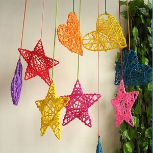 Detail showing various colorful rattan star and heart shaped ornaments hanging by a wall