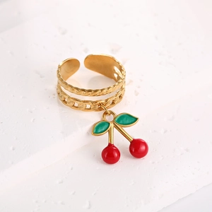 Detail of gold cherry charm ring with red enamel and twisted chain band design