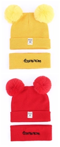 Detailed view of red and yellow knitted baby hats and headbands with faux fur pom-poms
