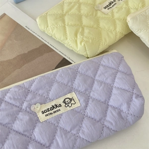 Macro detail of quilted fabric cosmetic bag with heart button and woven label accents