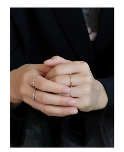 Close-up of minimalist geometric faceted rings stacked on a model against a black suit
