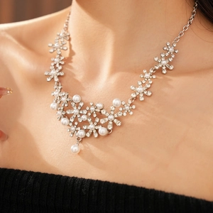 Detailed view of silver flower necklace with pearls and rhinestones on a model