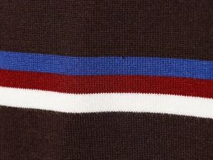 Nahaufnahme der Stricktextur mit blau-rot-weißen Streifen auf dunkelbraunem Hintergrund