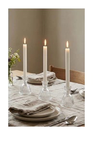 Detailed view of striped glass skirt candle holders and white tapered candles on table