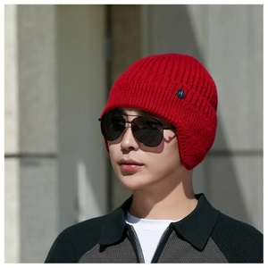 Detail of red winter knit hat featuring ear protection and thick vertical ribbing texture