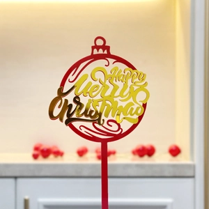 Macro detail of red and gold acrylic Merry Christmas cake topper ornament with mirror finish