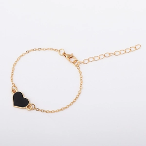 Dettaglio del bracciale a catena dorata regolabile con un ciondolo a cuore nero