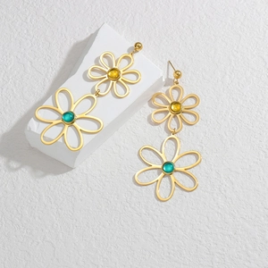 Close-up of 18K gold hollow flower earrings with yellow and green gemstones