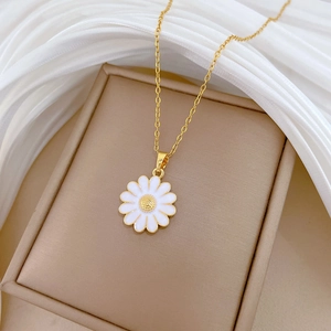 Detailed close-up of a daisy pendant with white petals and gold core on a jewelry box