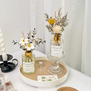 Detailed view of two 120ml glass aroma diffusers with dried flowers on a white tray