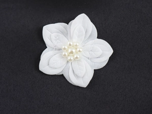 Close-up of a white fabric flower decoration with imitation pearl center on dress