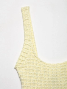 Close-up of the pale yellow knit fabric with grid texture and shoulder strap detail