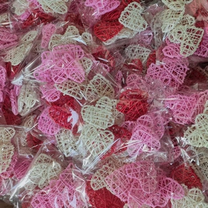 Detailed view of woven heart decorations in pink, red, and white individually packaged