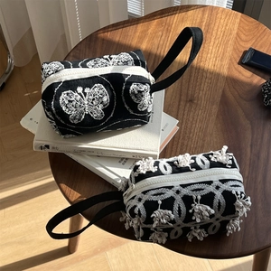 Detail of black canvas handbags with white butterfly embroidery and tassel fringe