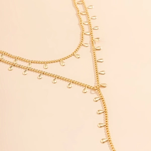 Close-up of bohemian layered gold necklace featuring delicate teardrop metal pendants