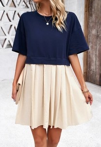 Dettaglio di top blu navy a maniche corte con gonna a pieghe beige e accessori