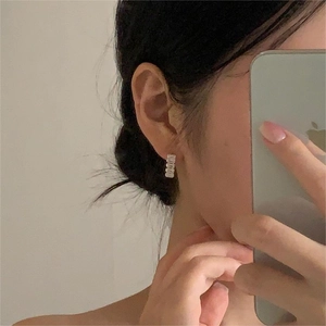 Close-up of minimalist sterling silver stud earrings with rectangle cubic zirconia on ear