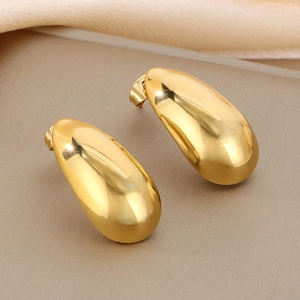 Polished gold teardrop earrings in a minimalist design on elegant champagne silk fabric