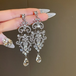 Macro detail of silver drop earrings with intricate baroque patterns and sparkling crystals