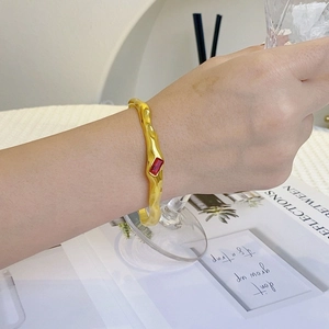 Chic gold C-shaped cuff bracelet with red rectangular zircon shown on a model's wrist