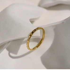Macro detail of gold-plated honeycomb ring with engraved heart patterns on a white stand