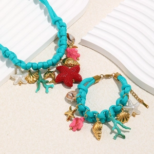 Flat lay of 18K gold-plated ocean-themed jewelry with blue rope and colorful pendants