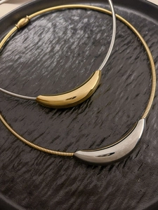 Detail of minimalist gold and silver curved pendant on sleek snake chain necklaces