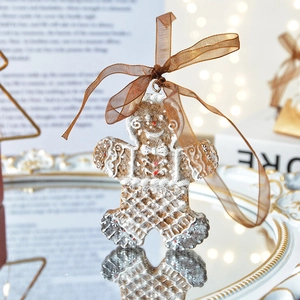 Festive gingerbread man resin ornament with silk bow on a mirrored tray with warm lights