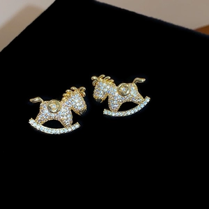Macro shot of 18K gold horse earrings with sparkling pavé crystals and clover details