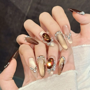 Luxury almond press-on nails with golden brown cat eye gradient and crystal bow details