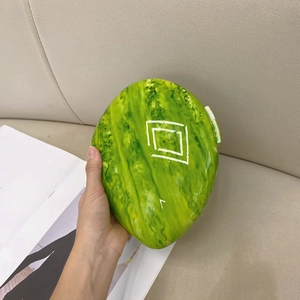 Detail of unique watermelon shaped hard shell clutch bag with marbled green texture