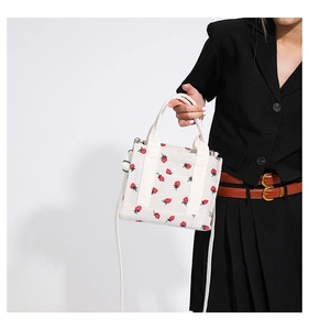Dettaglio della stampa a fragola su borsa in velluto beige con anello a D in metallo